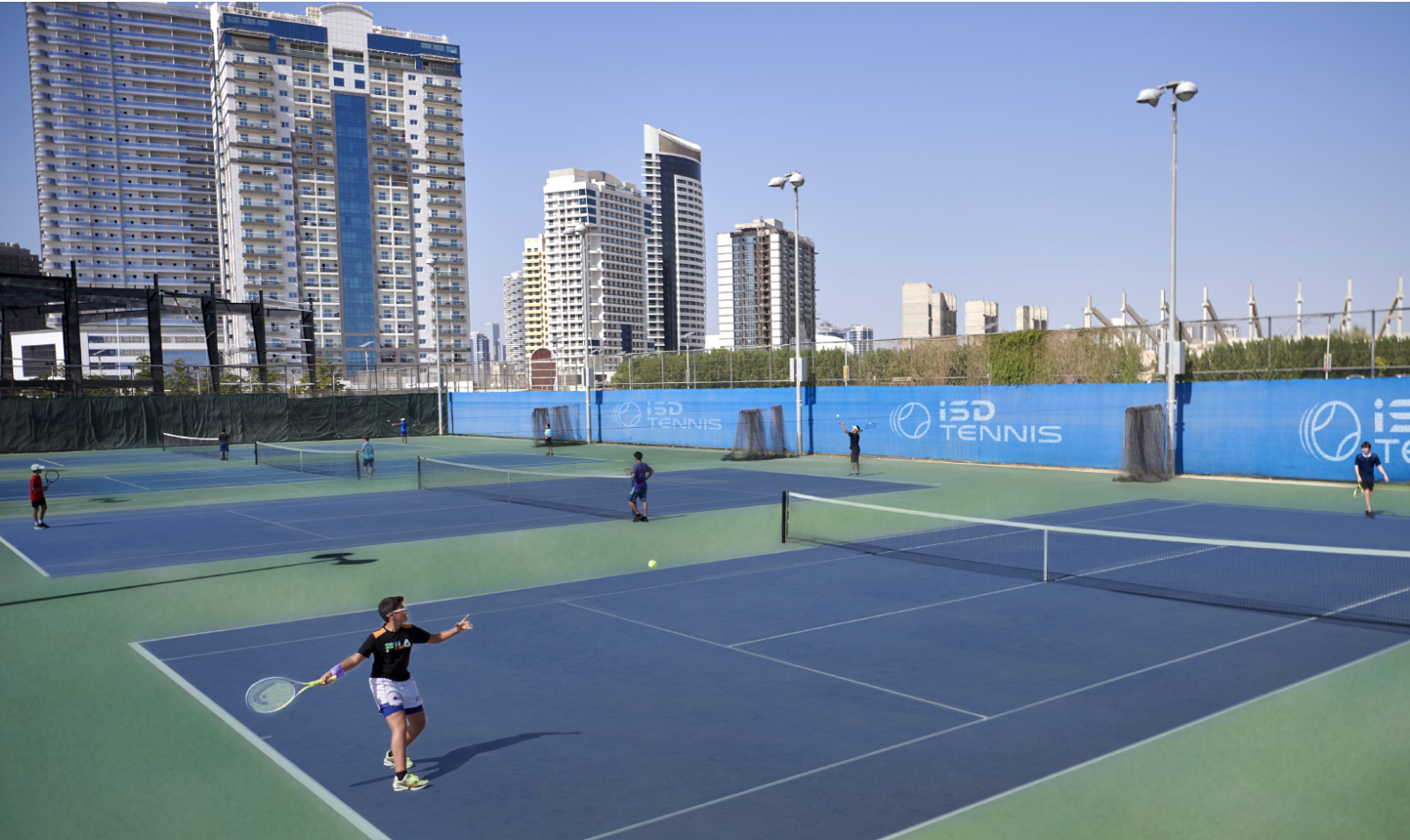 A young tennis player playing a practice match at ISD Tennis Academy Dubai